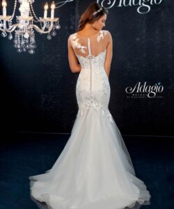 A woman in a white, lace-accented mermaid wedding dress stands with her back facing the camera.