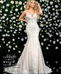 Woman wearing an embellished ivory mermaid gown stands in front of a wall decorated with white and yellow flowers.