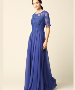 Woman wearing a floor-length, royal blue gown with lace bodice and short sleeves, standing against a plain background.