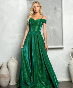 A woman in a shimmering green off-the-shoulder gown stands in front of a textured gray and white background with vases.